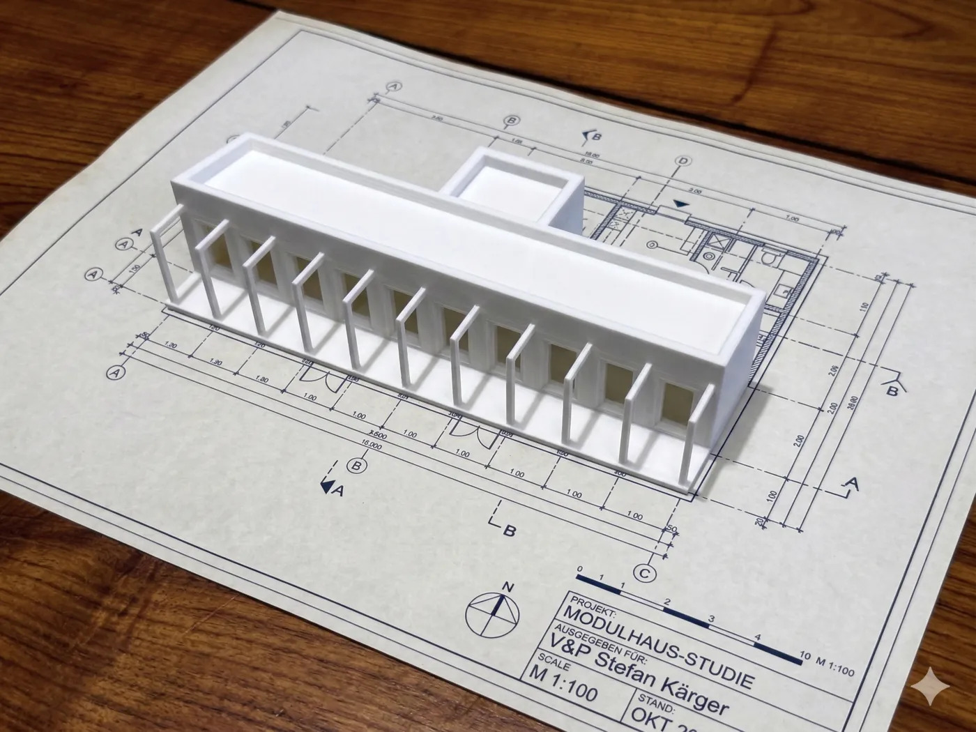 3D-gedrucktes Modell eines langgestreckten Modulhauses auf dem Grundrissplan